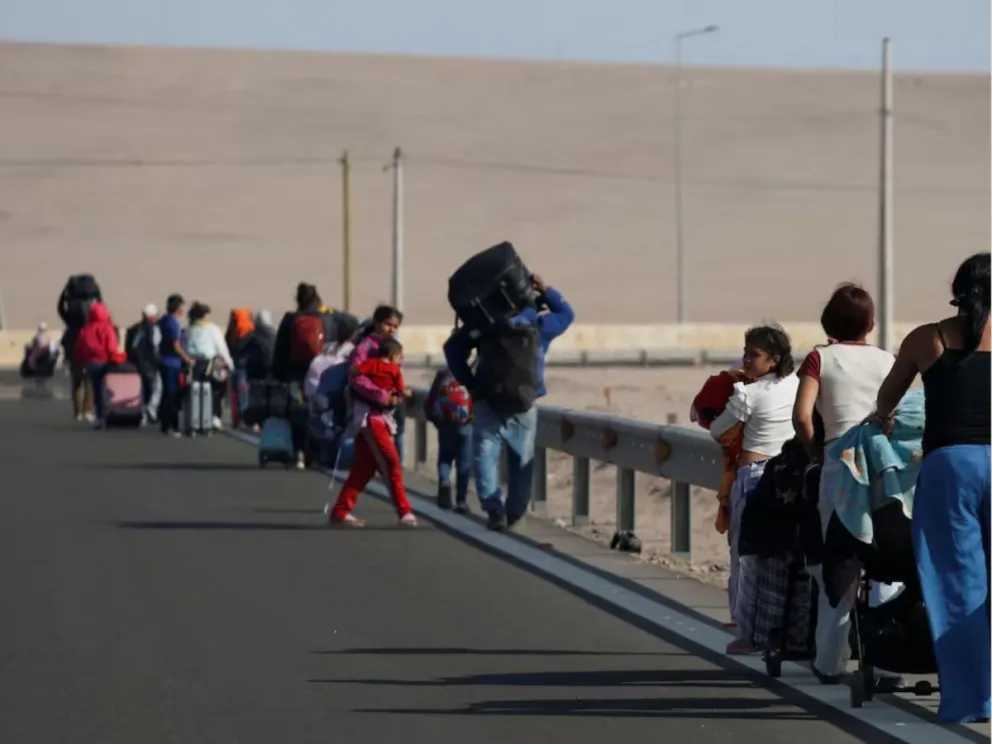 Migrantes venezolanos que intentan salir de Chile caminan por la carretera mientras regresan a Arica desde el Complejo Fronterizo de Chacalluta tras no lograr cruzar a Perú
