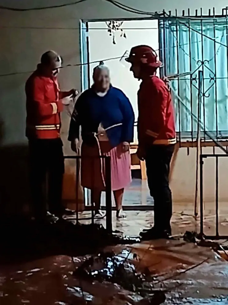 Bomberos junto a la mujer rescatada de 62 años 